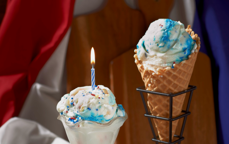 Child holding ice cream cone in front of American flag