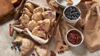 Some scones with blueberries and raspberries siting next to them.